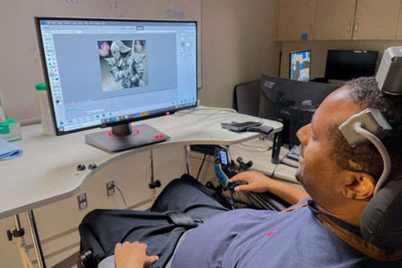 Person with brain-computer interface (BCI) interacting with computer.