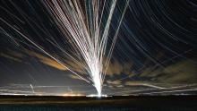 time-lapse photograph of planes at night showing many paths out of a single hub