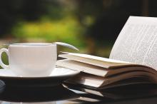 Open book with tea cup outdoors