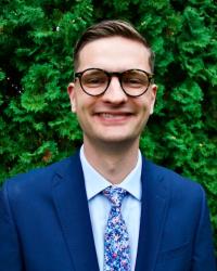 A picture of me wearing a suit and standing in front of a hedge